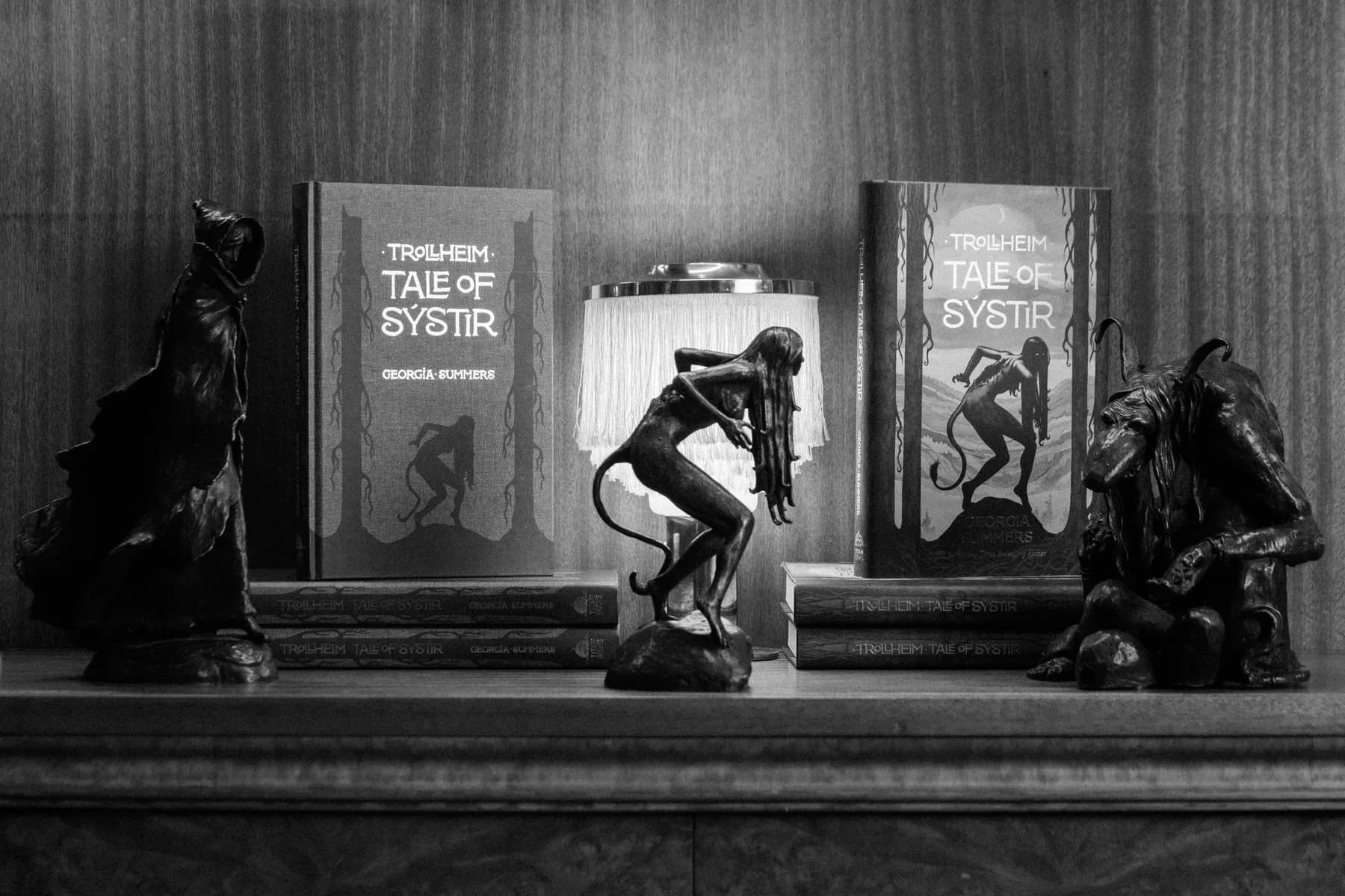 Trollheim books and sculptures arranged on a wooden shelf